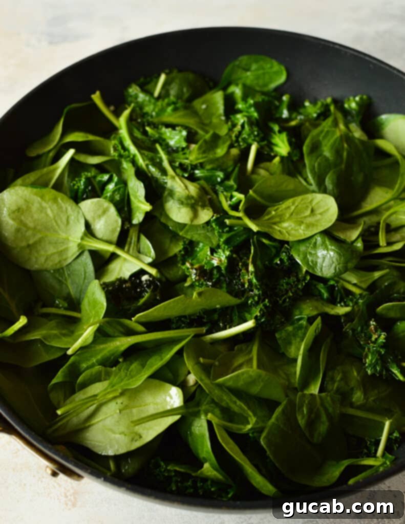 Sauteed kale with baby spinach being mixed in, just starting to wilt.