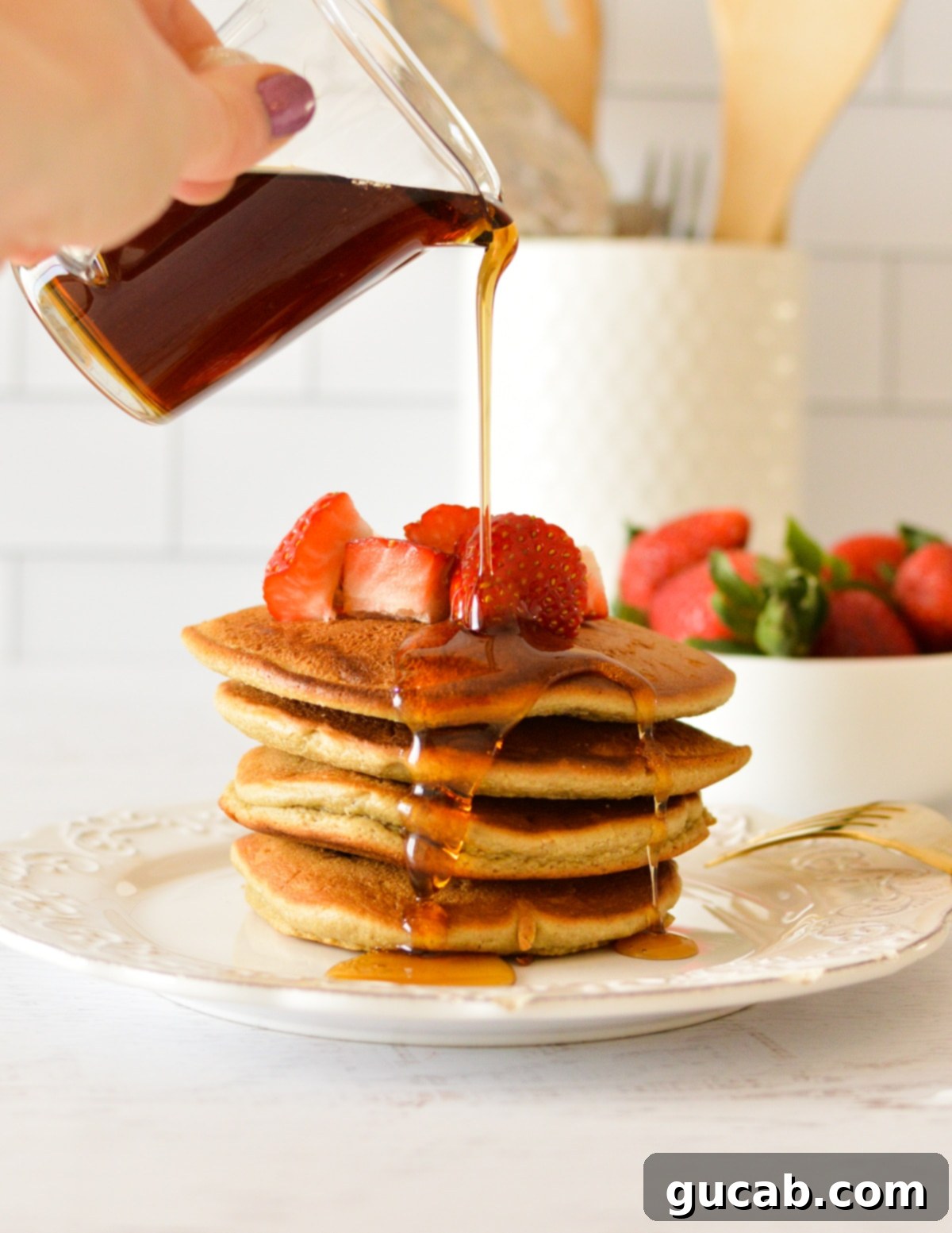 Light and Fluffy Oat Flour Pancakes 2 A plate of fluffy oat flour pancakes drizzled with maple syrup and fresh strawberries, ready to enjoy.
