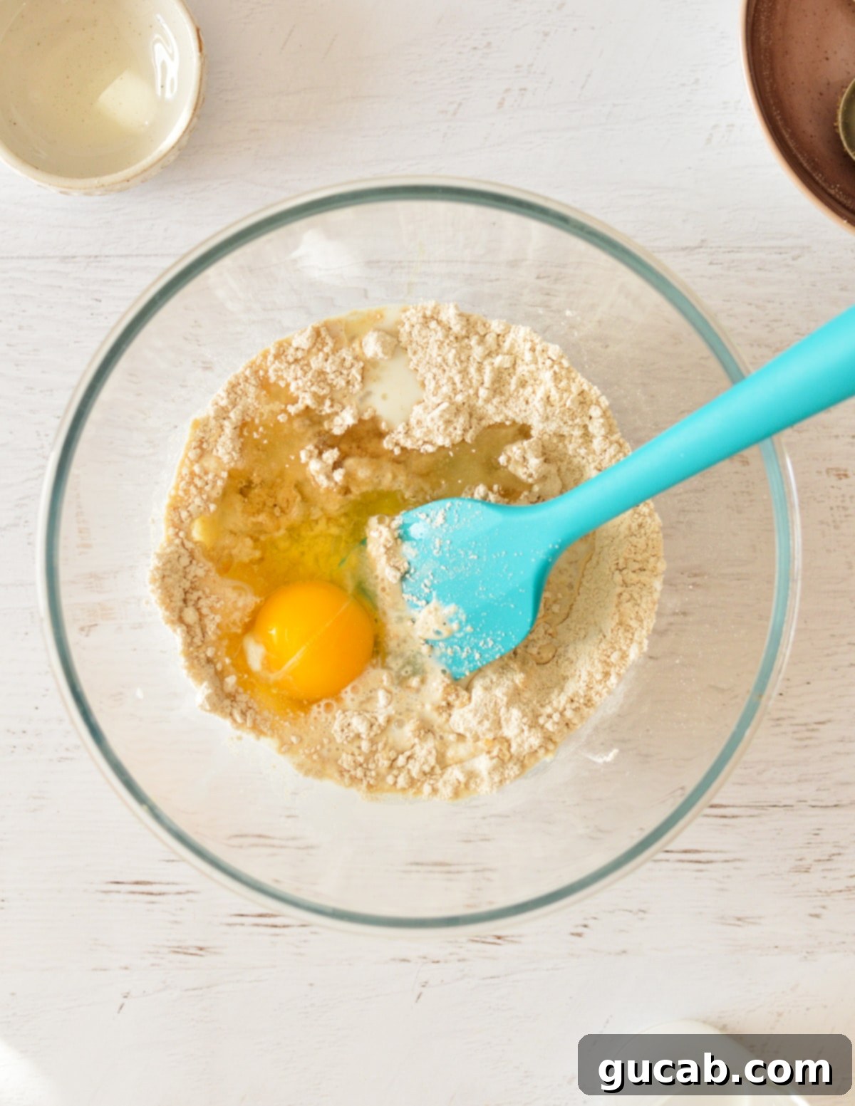 Light and Fluffy Oat Flour Pancakes 6 Wet ingredients including eggs being added to oat flour in a mixing bowl.