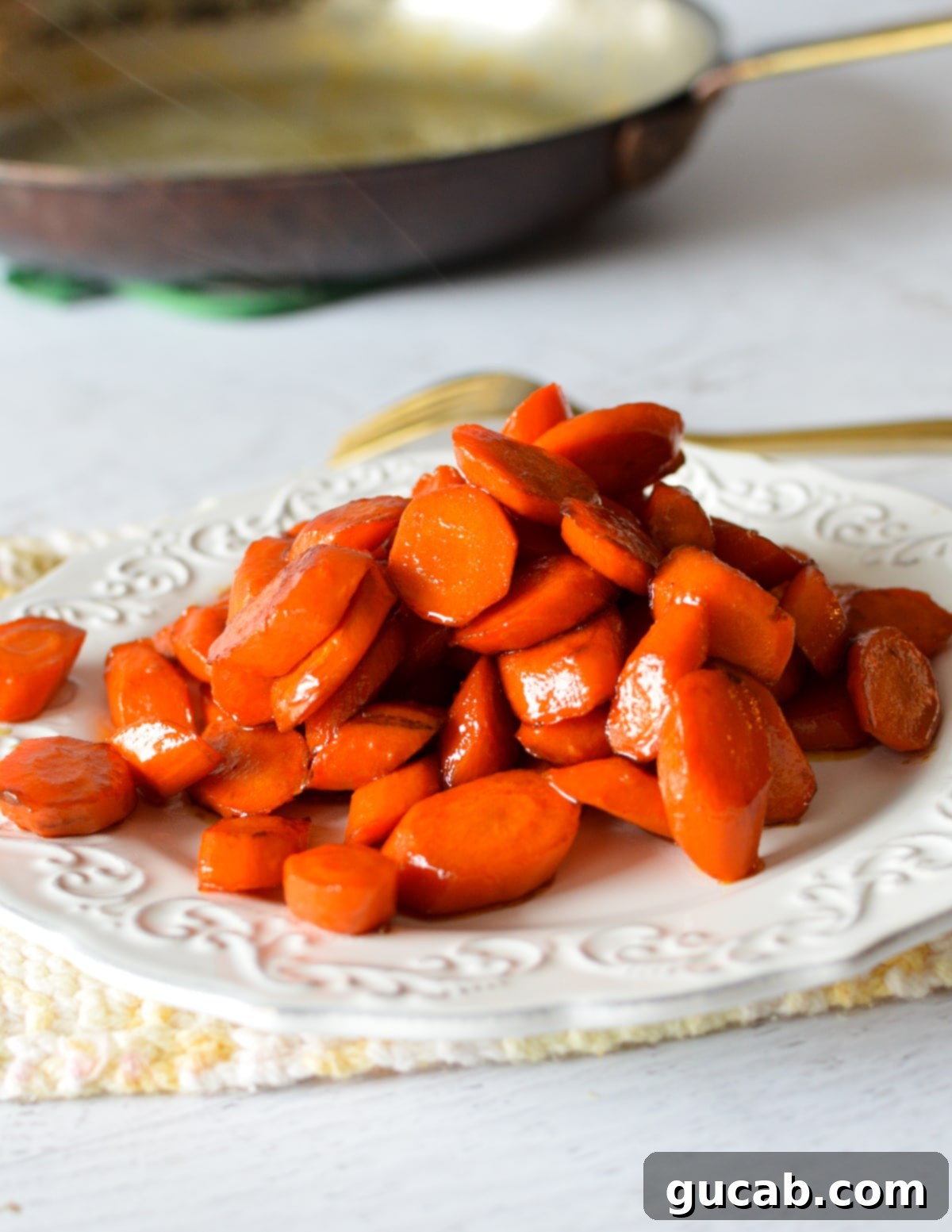 close-up of glistening maple glazed stovetop carrots on a white plate, ready to be served, showcasing their vibrant orange color and sweet coating.