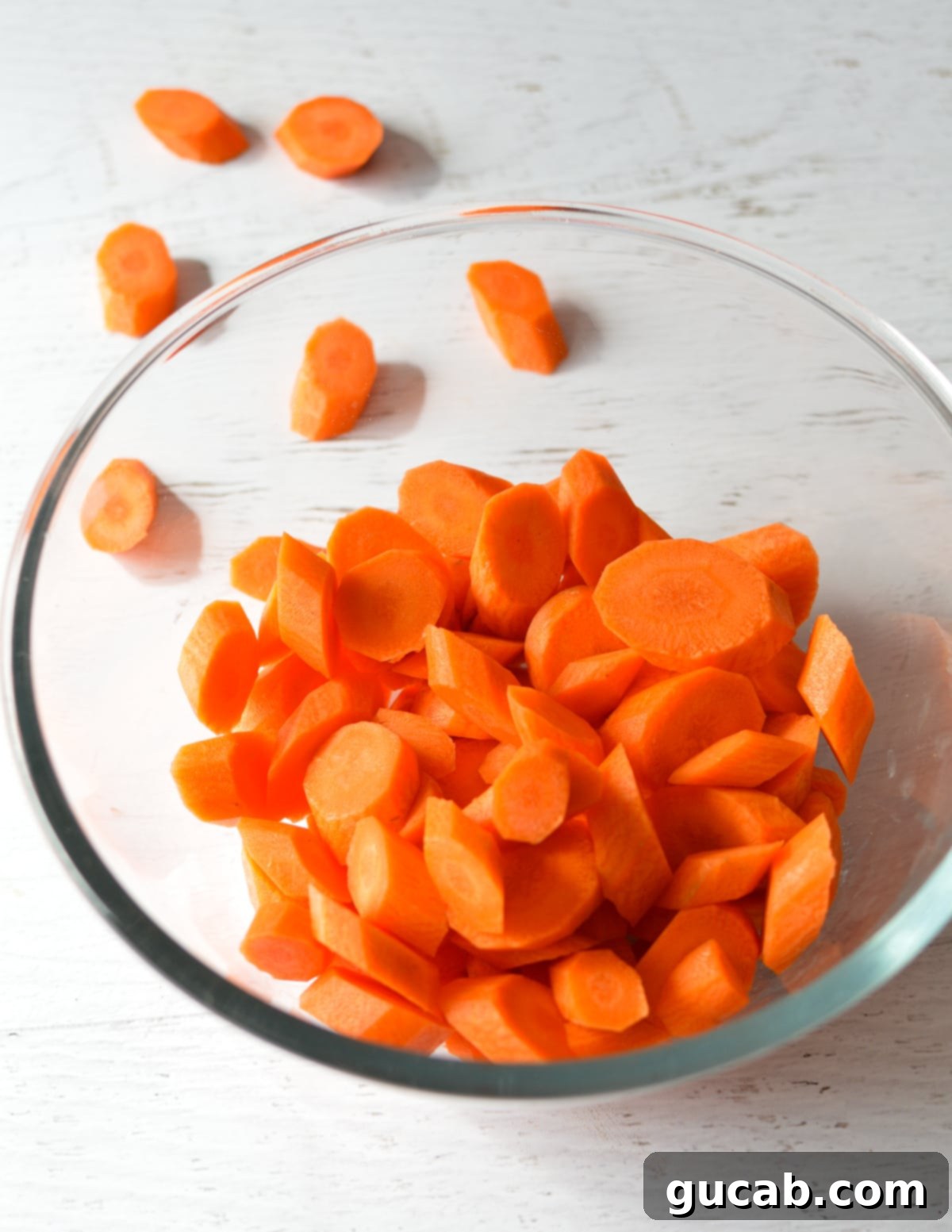 a bowl filled with freshly cut and peeled carrots, ready for cooking, highlighting their uniform diagonal slices.