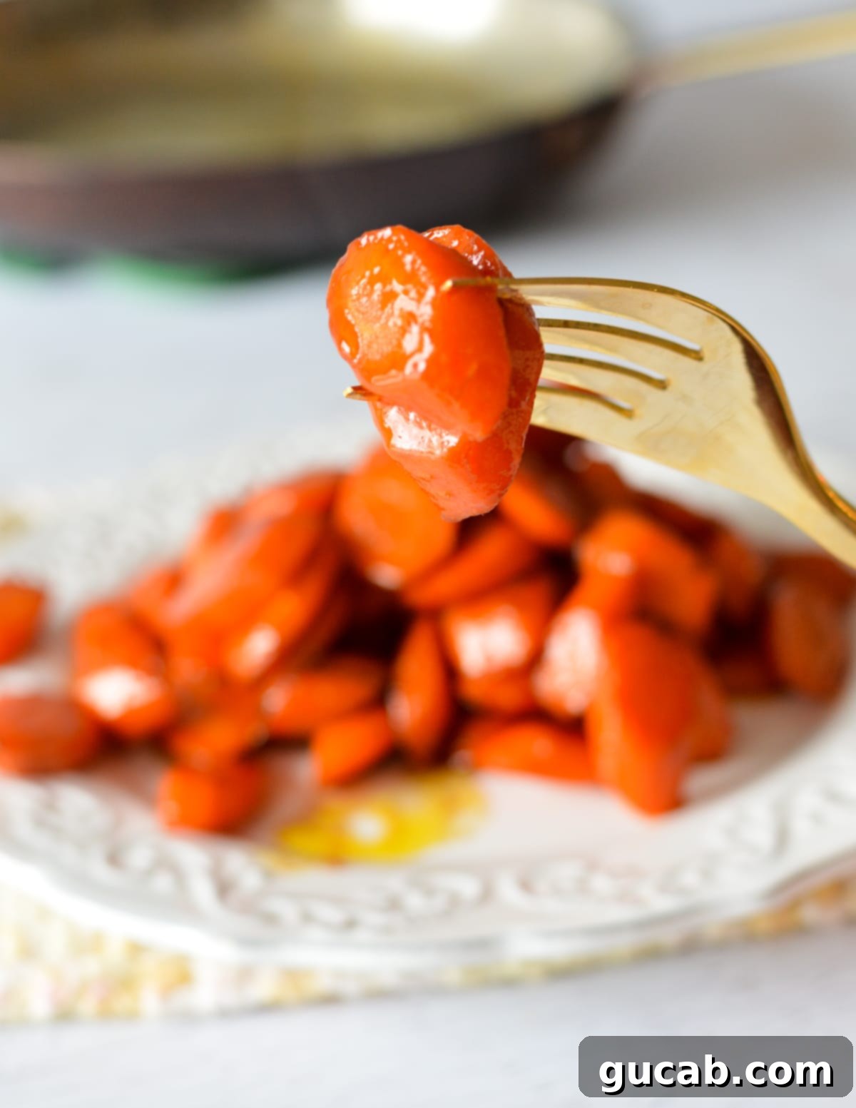 a close-up shot of a single maple glazed carrot slice on a fork, showing its tender texture and the sticky, sweet glaze.