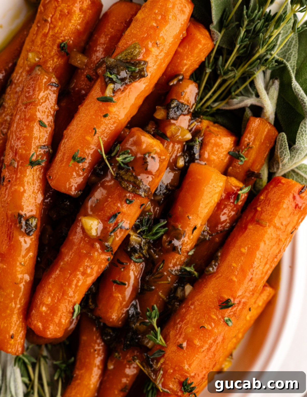 Maple-Glazed Roasted Carrots 2 Maple roasted carrots garnished with fresh thyme and sage in a baking dish.