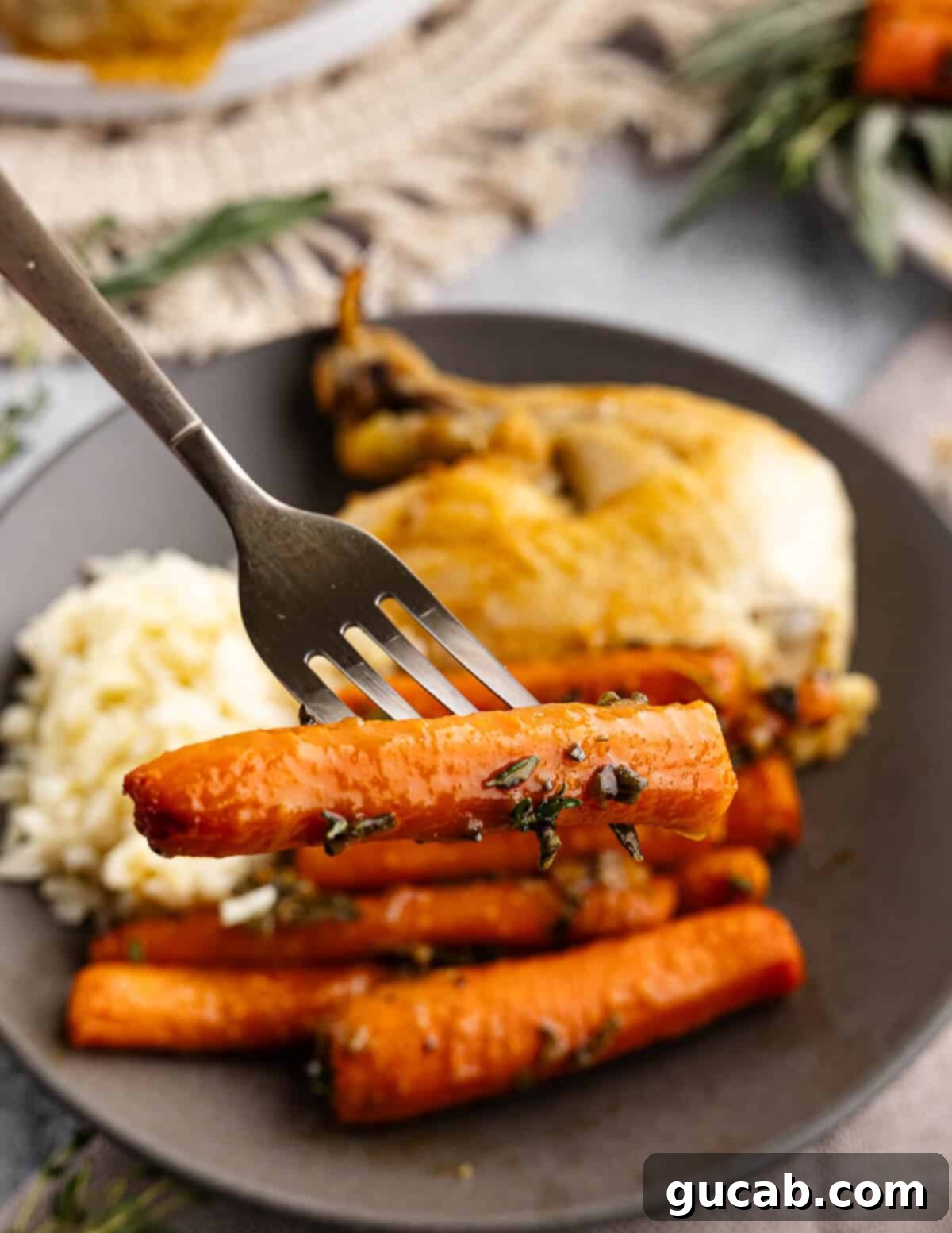 Maple-Glazed Roasted Carrots 4 fork holding a roasted carrot with herbs on it.
