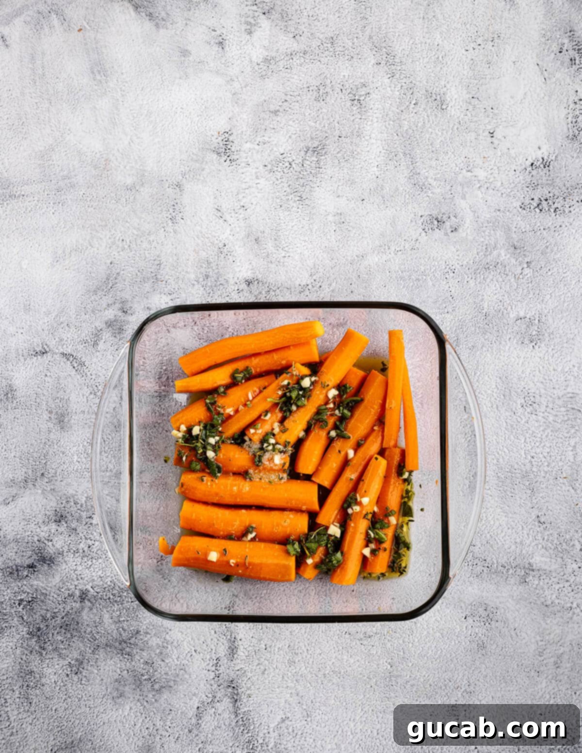 Maple-Glazed Roasted Carrots 8 halved carrots coated in maple garlic sauce in a baking dish.