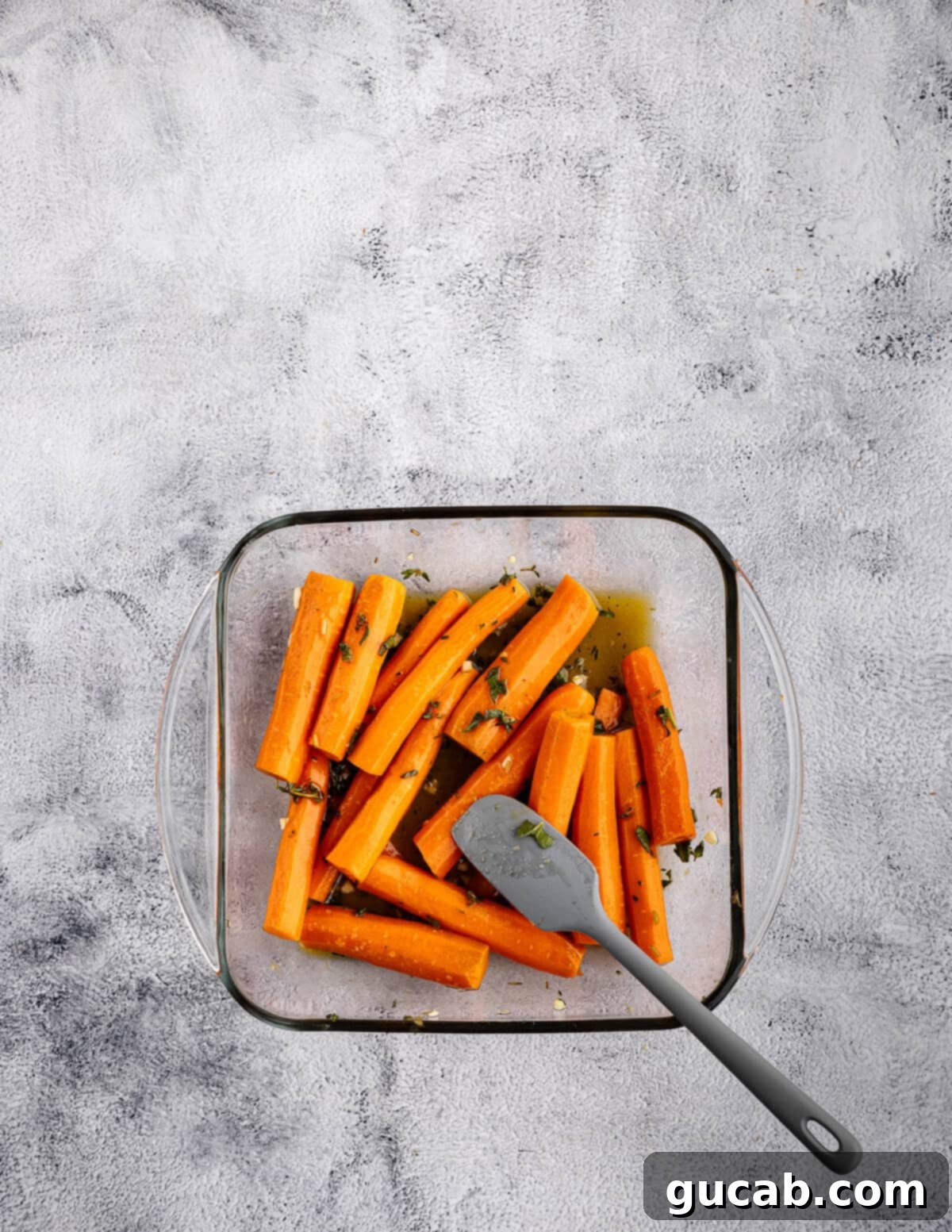 Maple-Glazed Roasted Carrots 9 spatula stirring carrots coated in maple sauce.