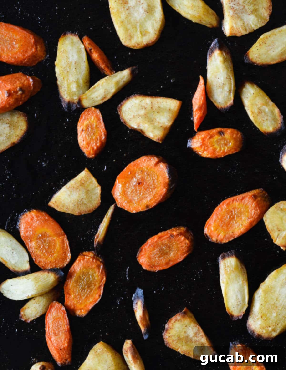Close up of beautifully roasted carrots and parsnips on a sheet pan, showing their tender texture and golden-brown edges.