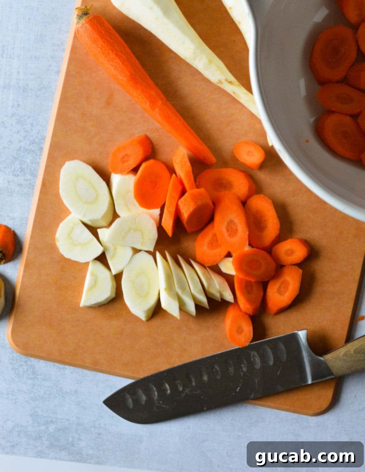 Sliced carrots and parsnips, uniformly cut into ½-inch thick rounds on a cutting board, ready for coating.