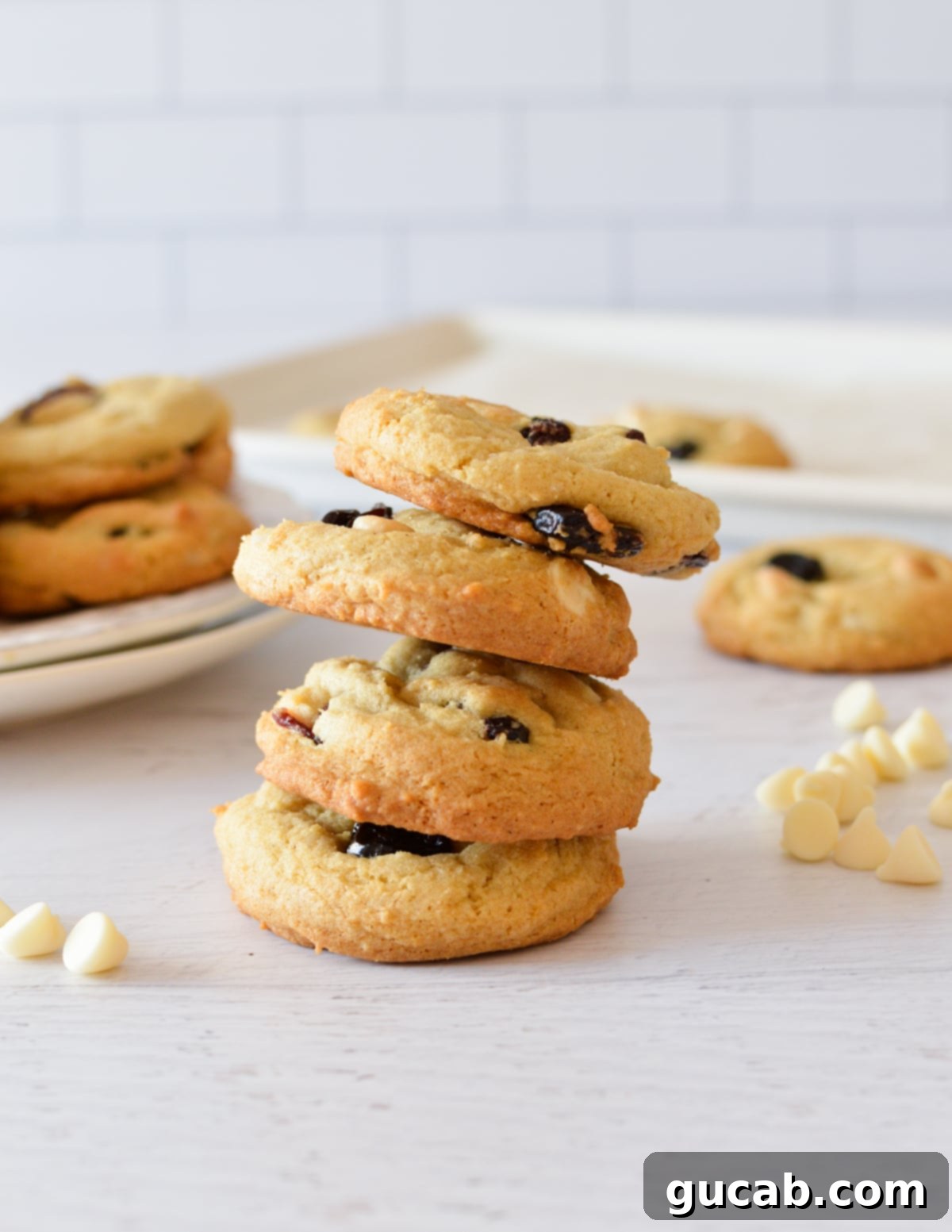 A stack of perfectly baked dried cherry and white chocolate cookies, showing their soft, chewy texture and abundance of mix-ins.