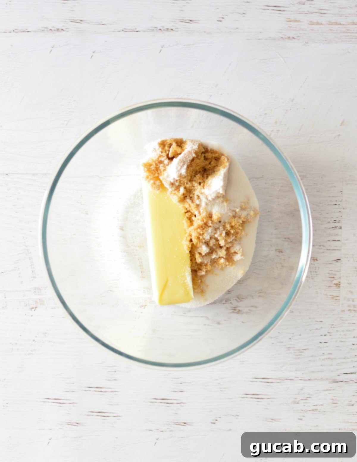 Unsalted butter, granulated sugar, and brown sugar measured out in a mixing bowl before creaming.
