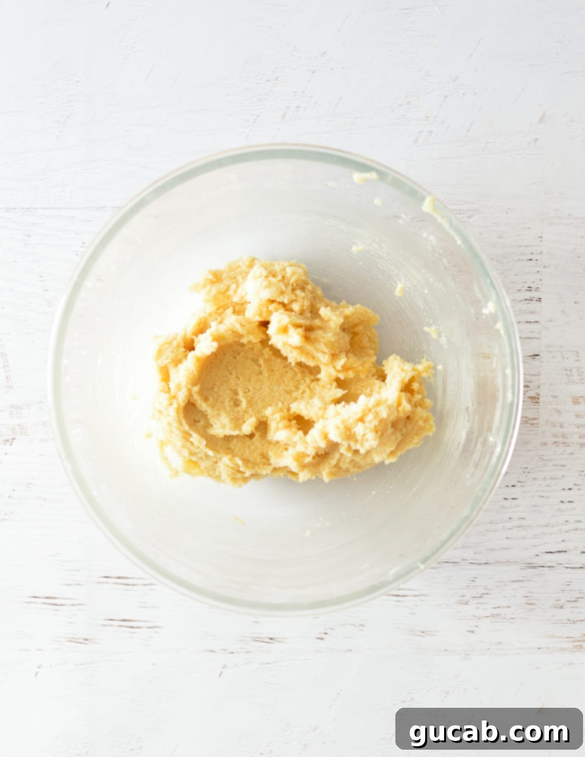 The butter and sugars have been creamed together, showing a light and fluffy texture in the bowl.