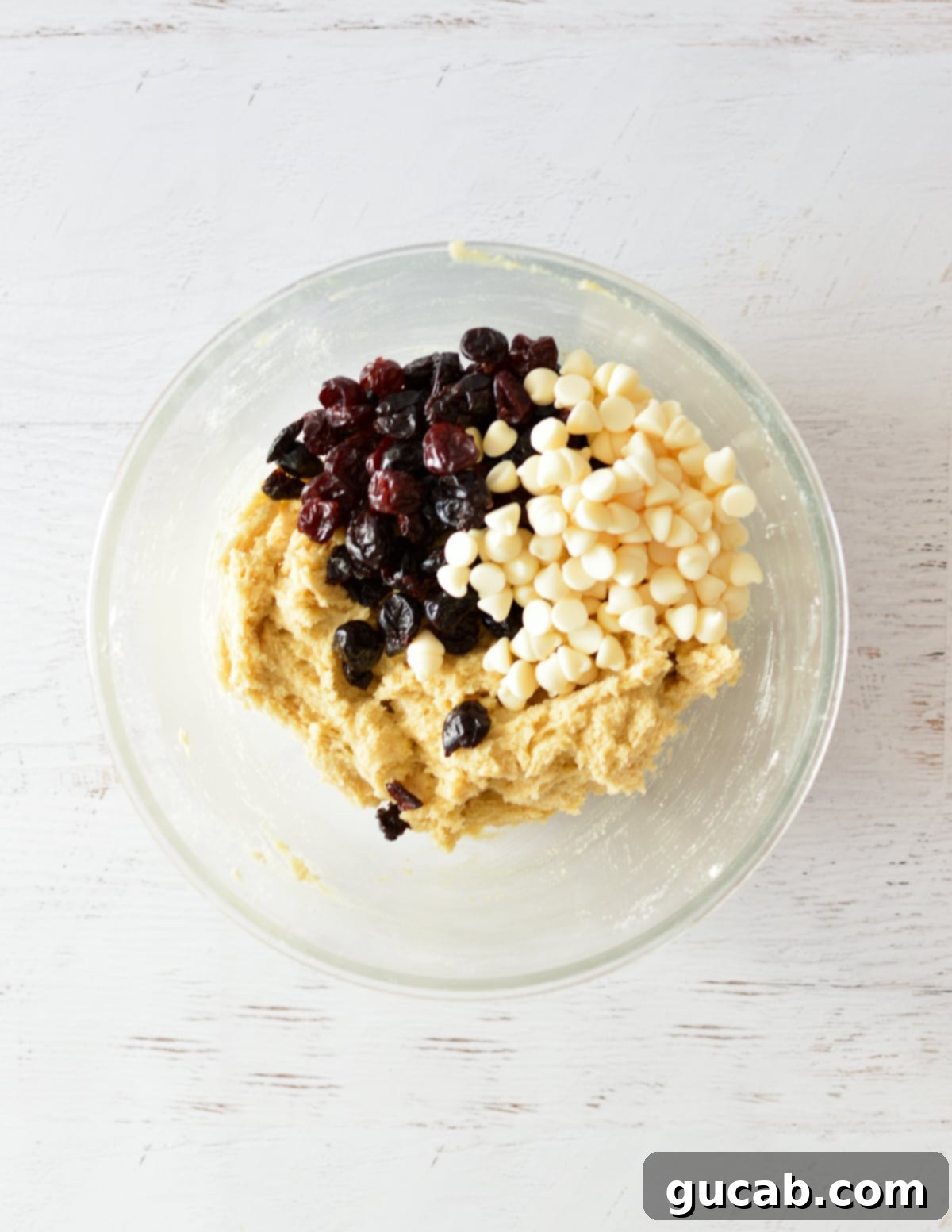 Finished cookie dough in a mixing bowl, studded with dried cherries and white chocolate chips, ready for scooping.
