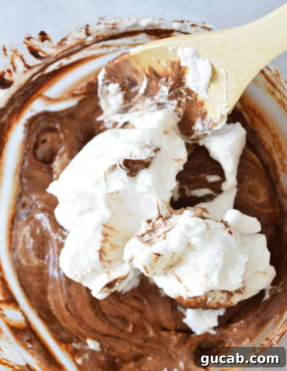egg whites getting stirred into chocolate mousse.
