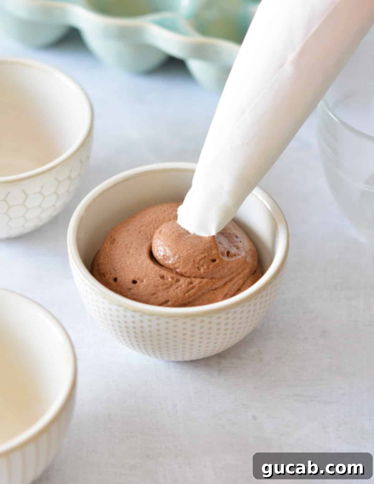 piping chocolate mousse into a small bowl.
