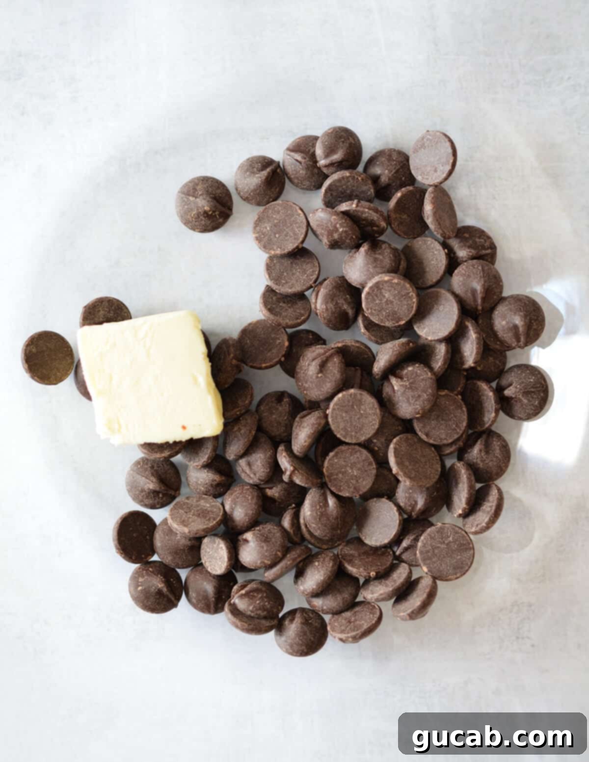 A bowl containing dark chocolate chips and cubes of butter, ready for melting.