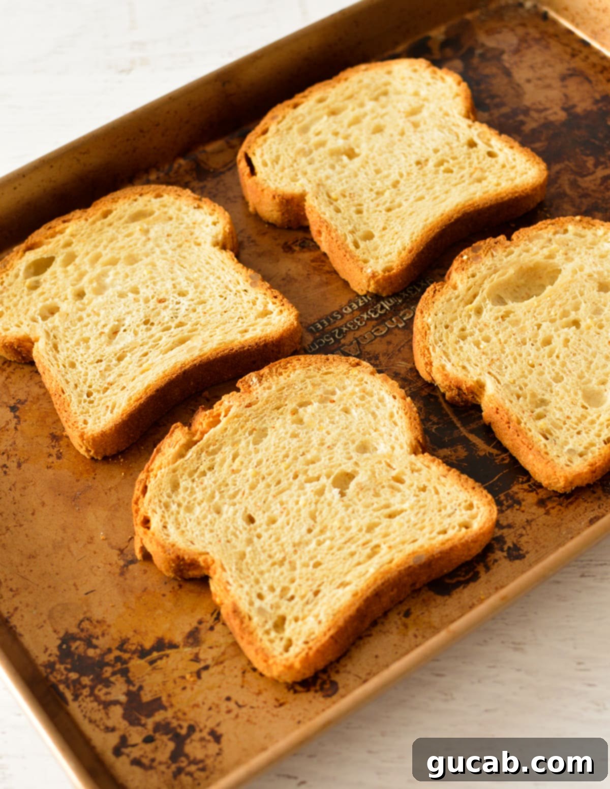 Four slices of bread neatly arranged on a baking sheet, ready for garlic butter.