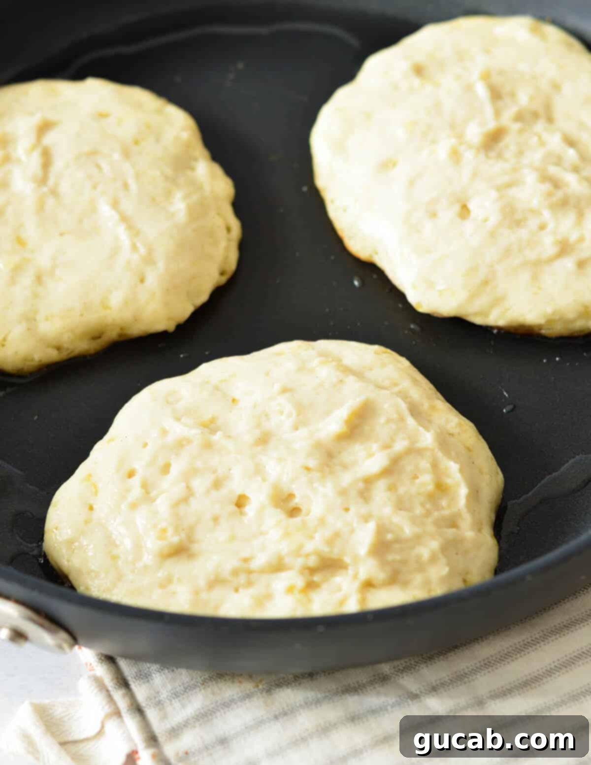 pancake batter being poured into a hot skillet.