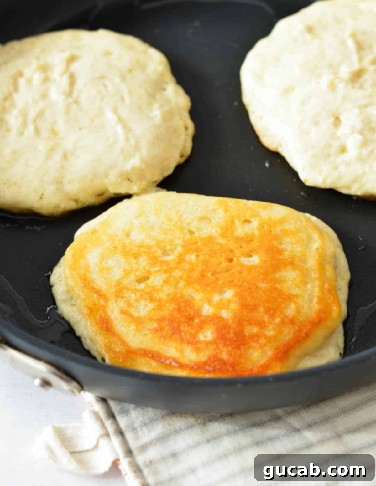 a fluffy pancake being flipped in a skillet.