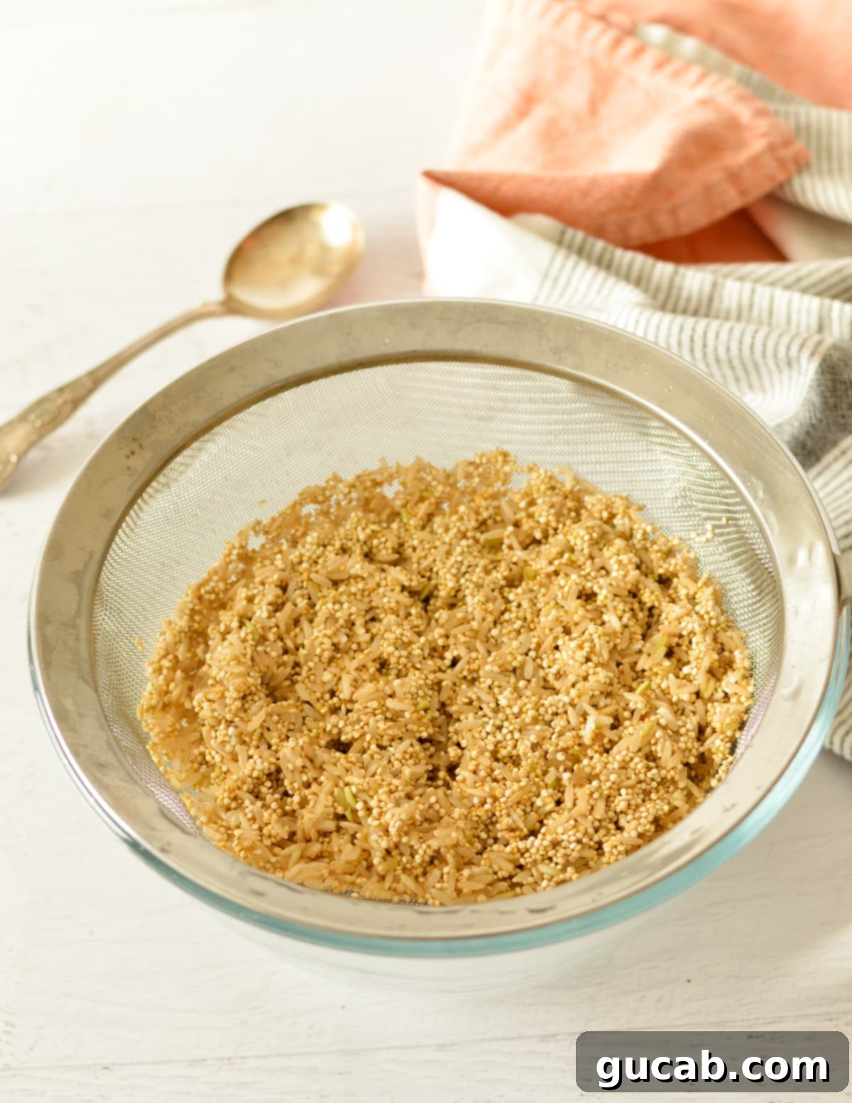 Close-up of brown rice and quinoa being rinsed in a fine mesh sieve under running water.