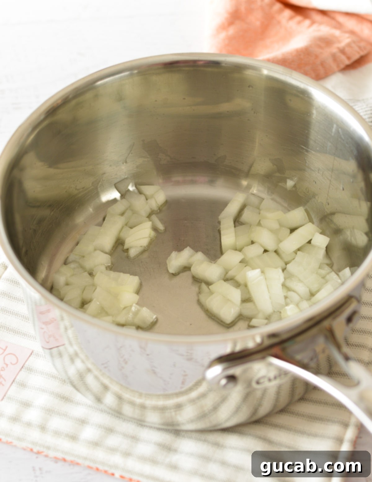 Onions sautéing in olive oil in a saucepan, becoming translucent.