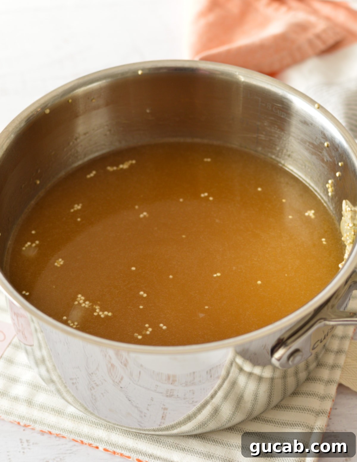 Brown rice, quinoa, and vegetable stock simmering in a saucepan, about to reach a boil.
