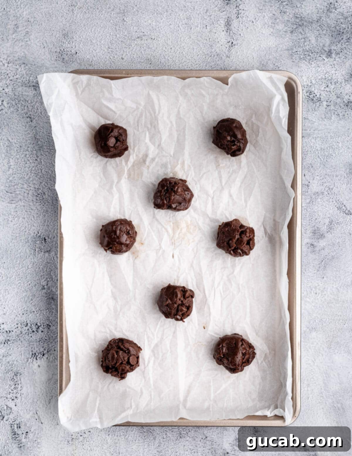 Decadent Gluten-Free Double Chocolate Delights 11 Eight perfectly scooped gluten-free chocolate cookie dough balls arranged on a parchment-lined baking sheet, ready for the oven.