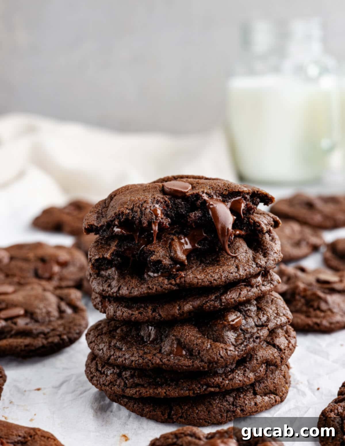 A stack of warm gluten-free double chocolate cookies, with gooey melted chocolate oozing out, on a white plate.