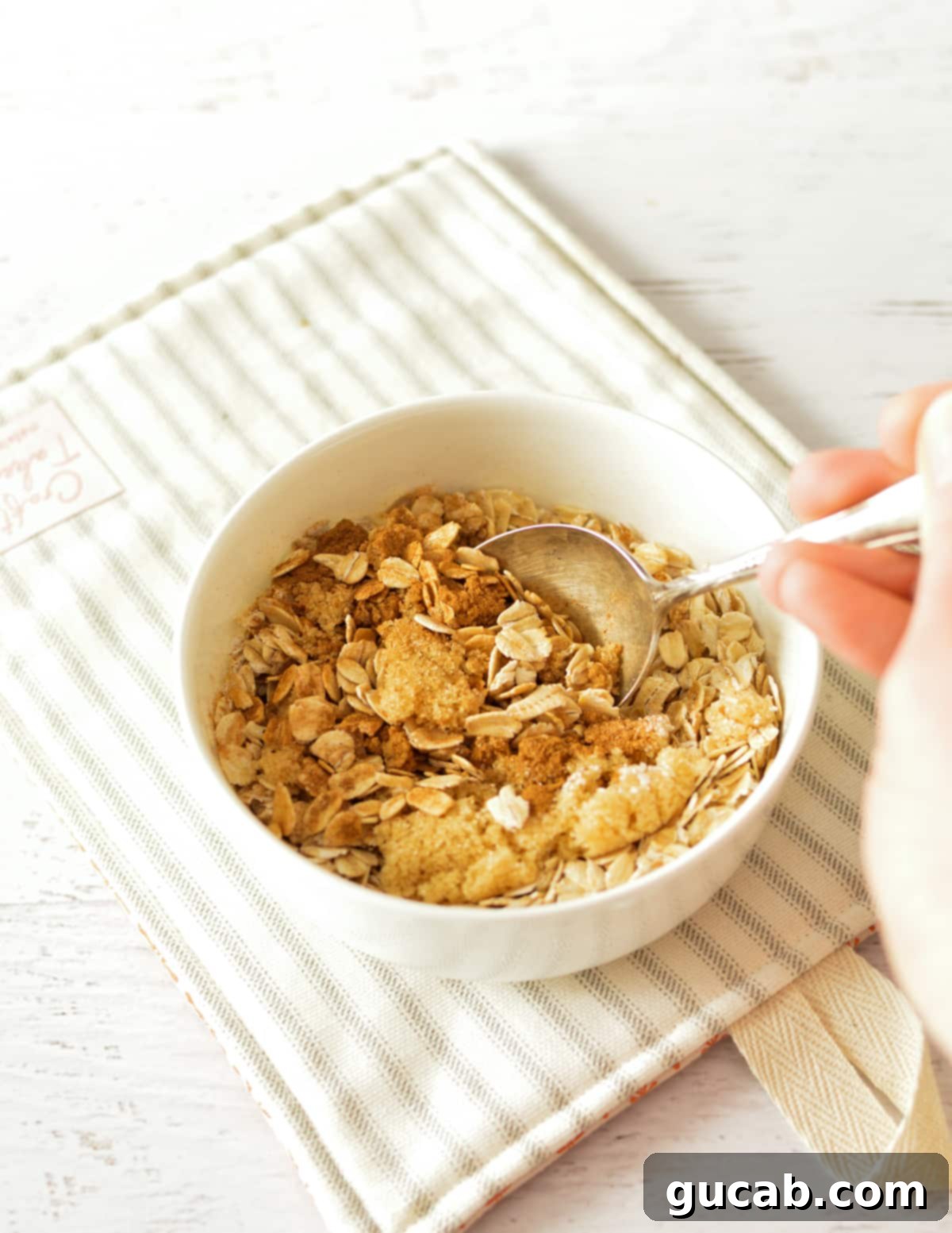 A close-up shot of a small bowl containing a mixture of rolled oats, brown sugar, ground cinnamon, and kosher salt, ready for cooking.