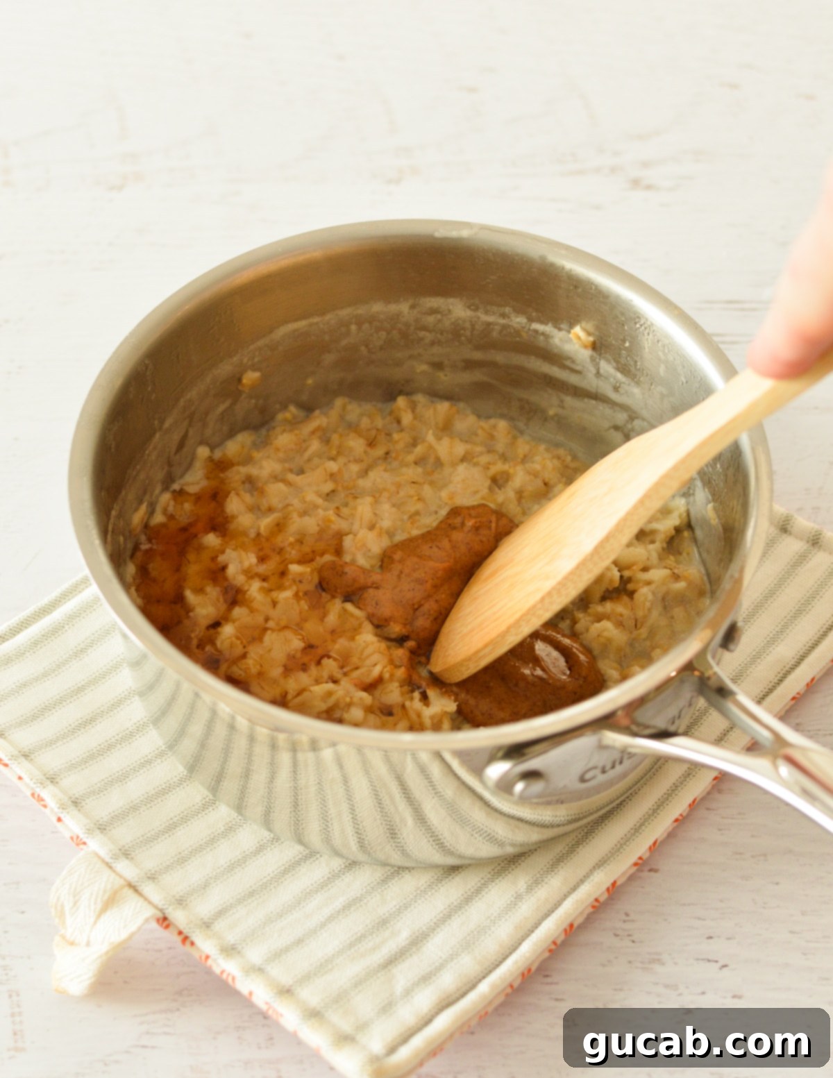 a saucepan of oatmeal with almond butter and maple syrup.