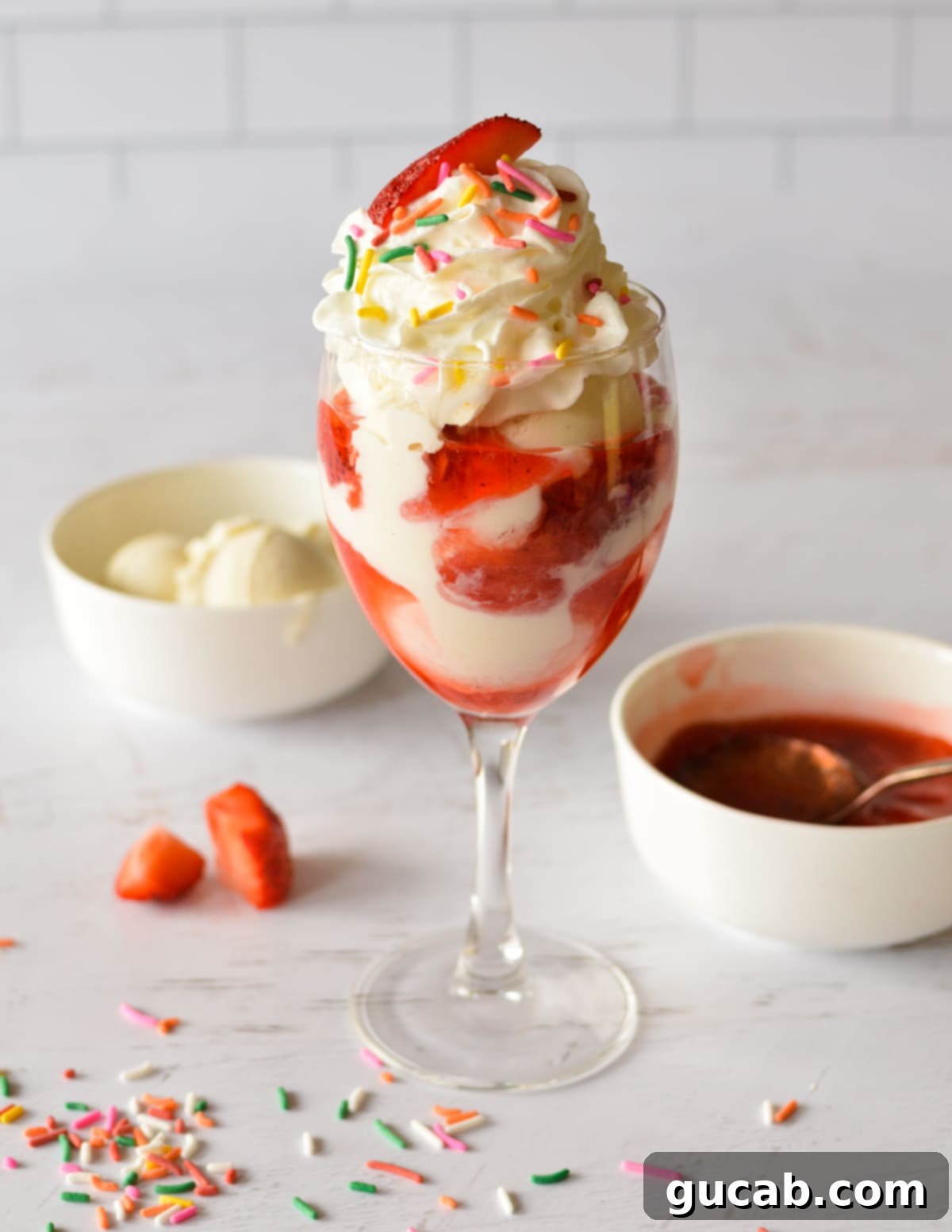 A strawberry sundae with whipped cream and sprinkles, presented beautifully in a glass.