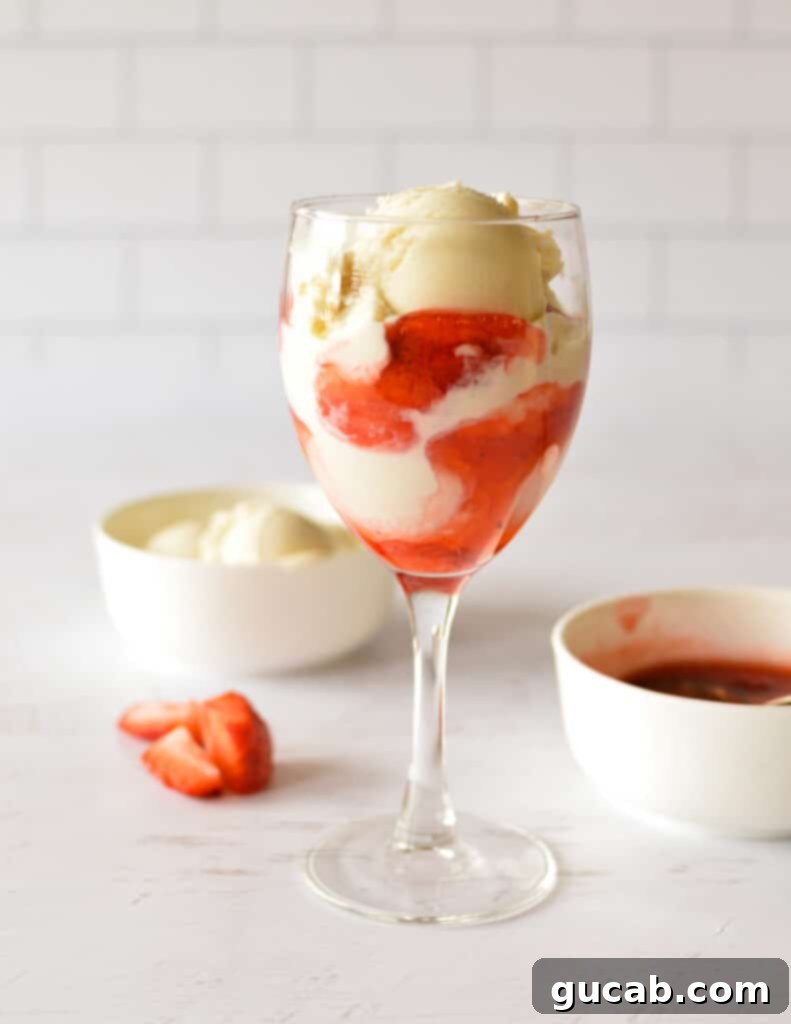 A strawberry sundae being topped with a large swirl of whipped cream.
