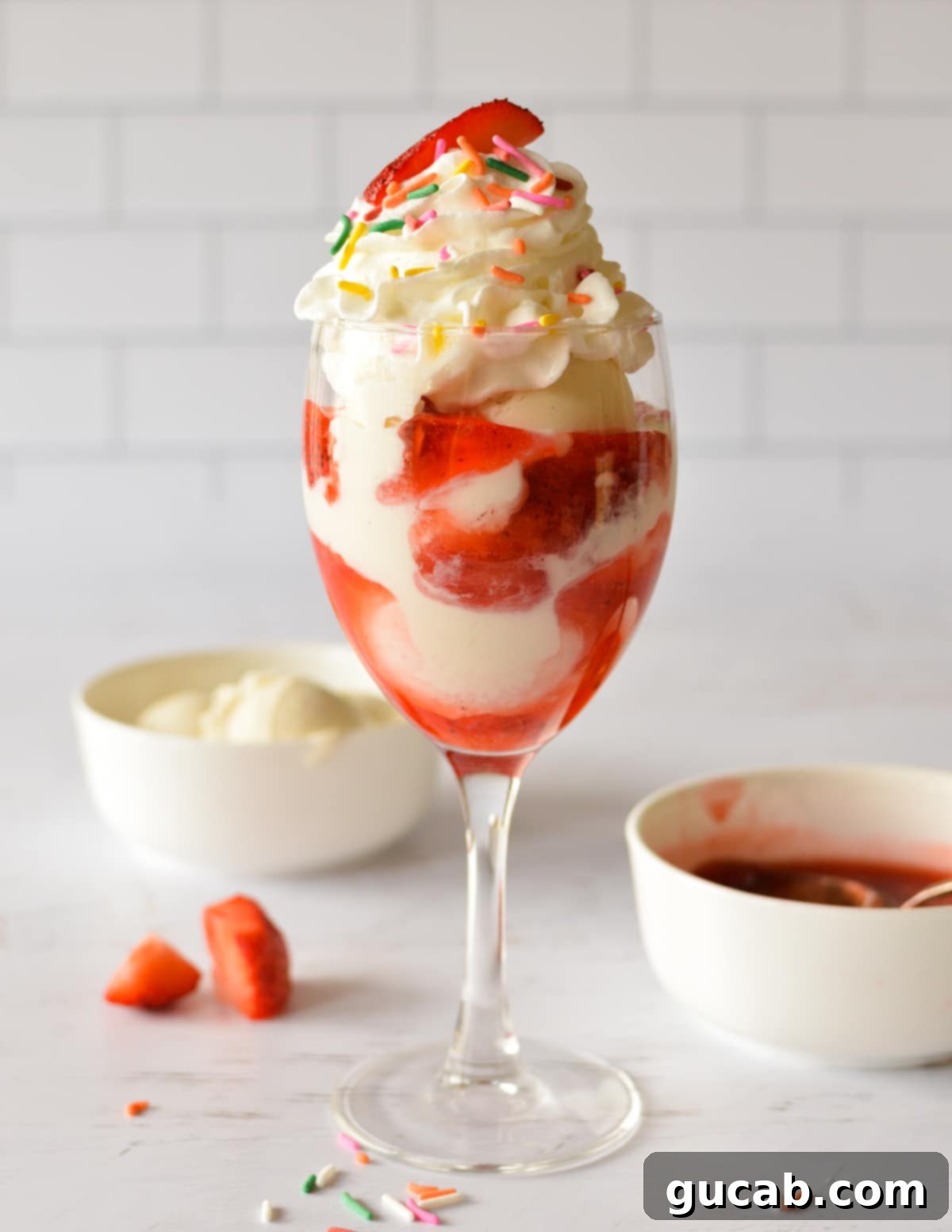 A close-up shot of a finished strawberry sundae with whipped cream, sprinkles, and a fresh strawberry, showcasing its tempting layers.
