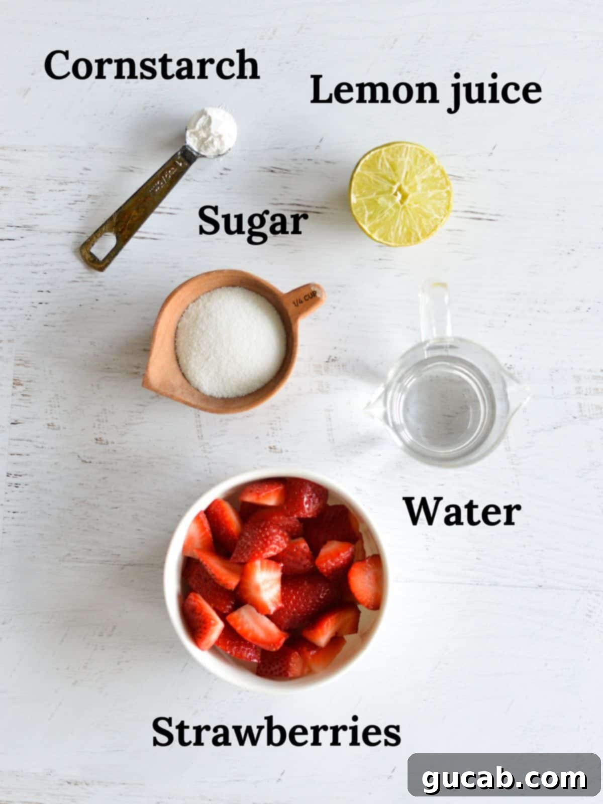 A flat lay showing cornstarch, lemon, sugar, water, and fresh strawberries, the core ingredients for the homemade sauce.