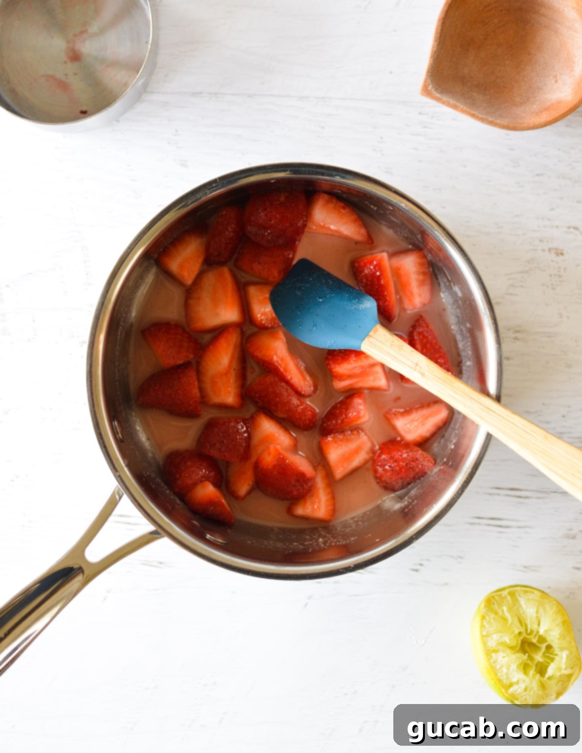 The strawberry mixture simmering gently in a pan, showing signs of thickening.