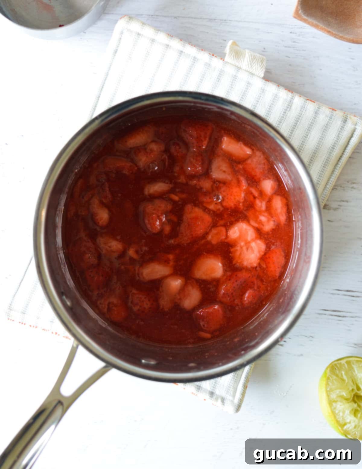 Cooked strawberries in a pan, now thickened into a sauce.