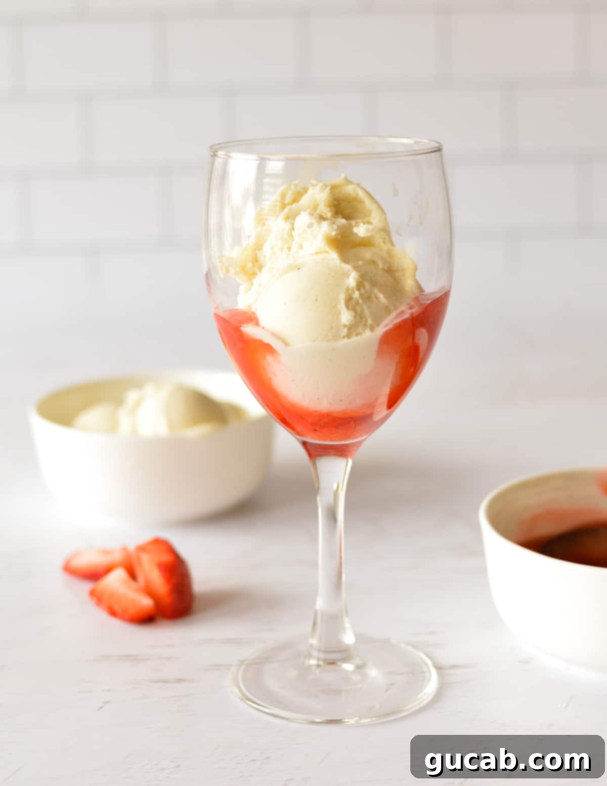 A glass with a layer of strawberry sauce topped with vanilla ice cream.