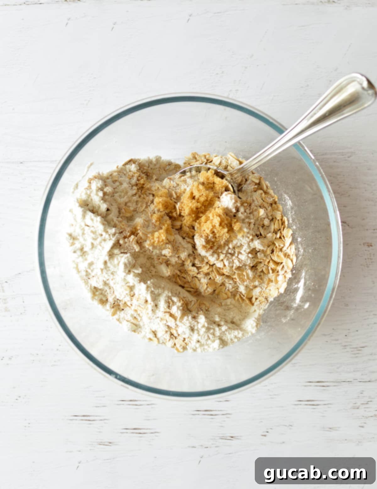 A bowl containing brown sugar, granulated sugar, oats, and flour mixed together.