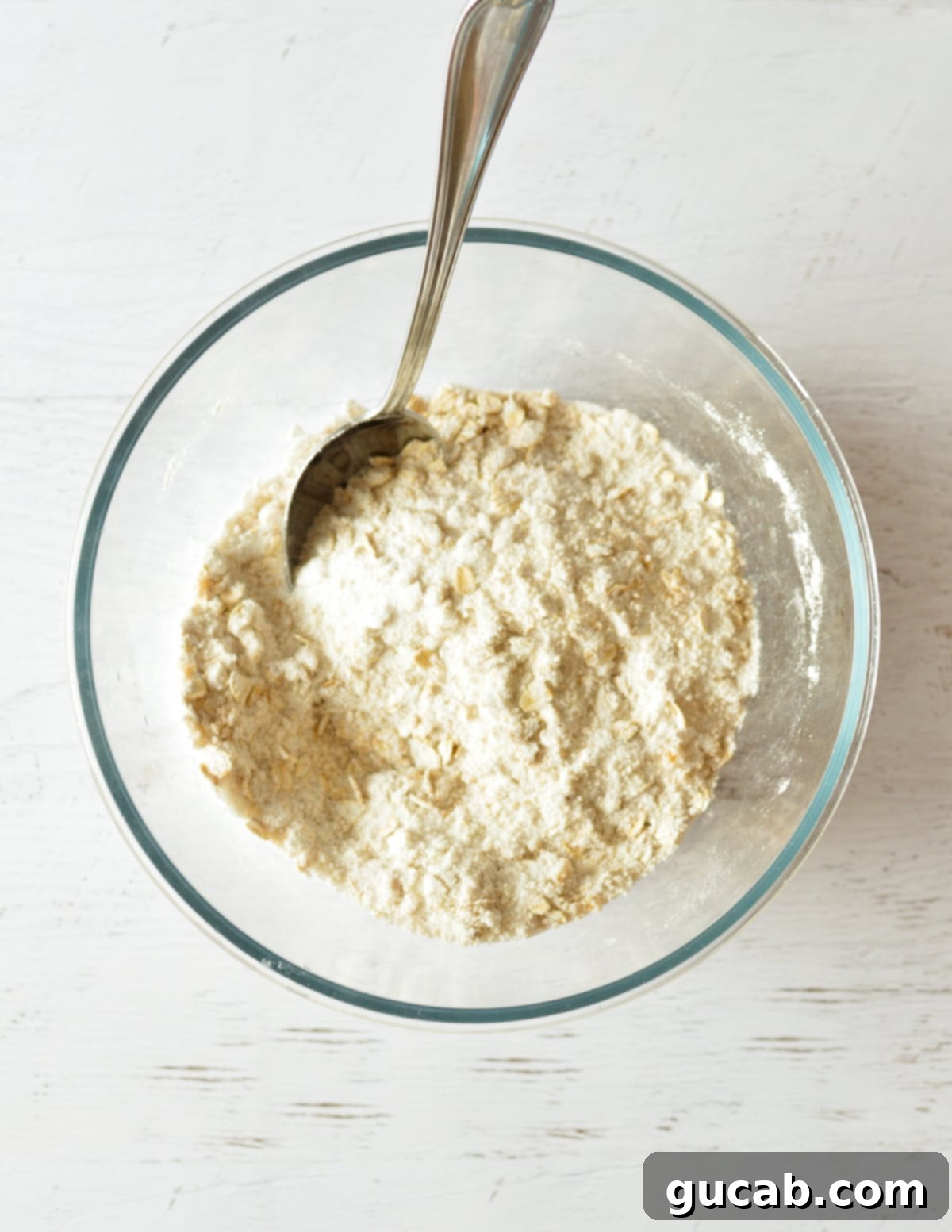A closer view of the well-combined flour, sugar, and oat mixture in a bowl.