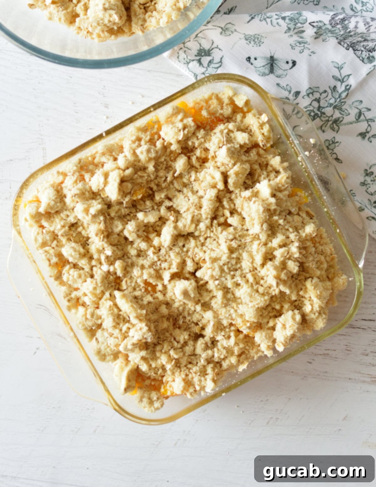 Pantry Peach Crisp Perfection 9 Unbaked peach crisp in a baking dish with the crumble topping spread evenly over the peaches.