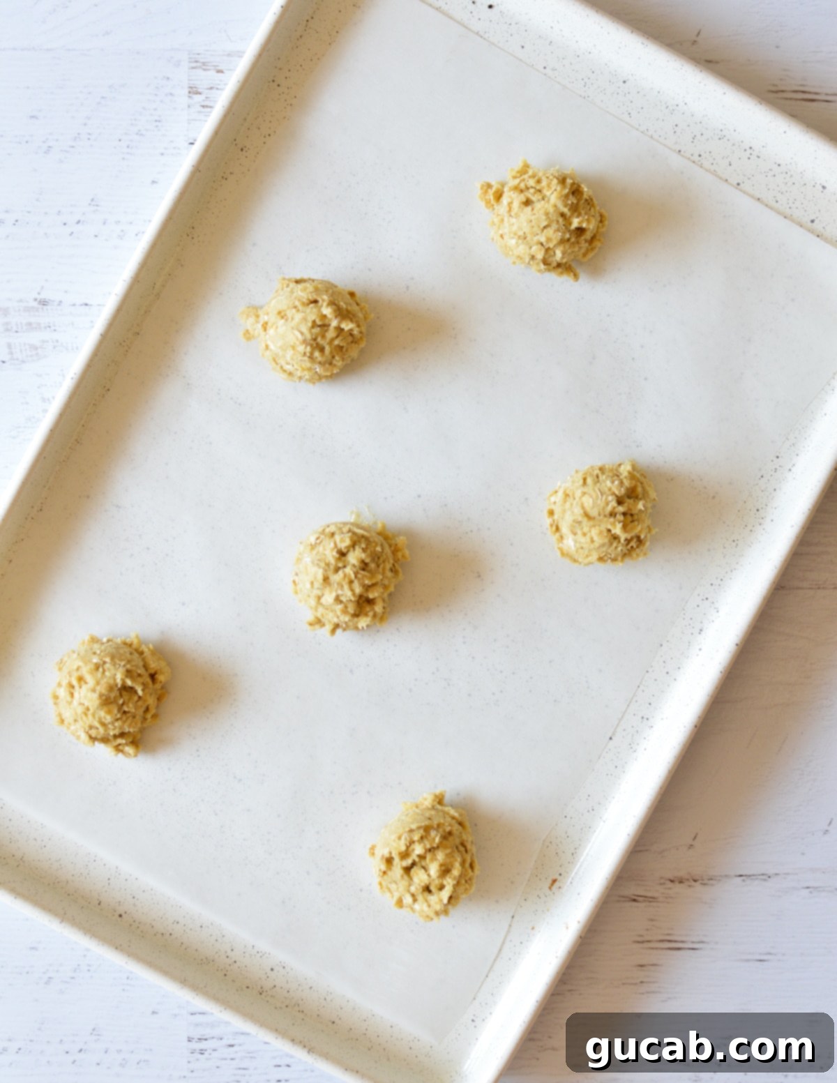 Soft and Chewy Oatmeal Bliss 10 oatmeal cookie dough balls on a sheet pan with parchment paper