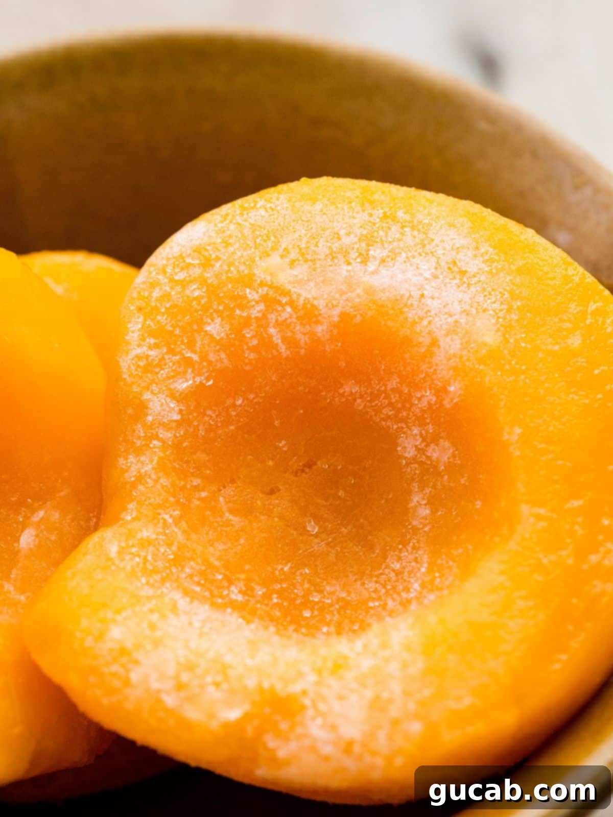 Sweet Chill: 15 Irresistible Frozen Peach Recipes 3 frozen peach halves in a bowl.