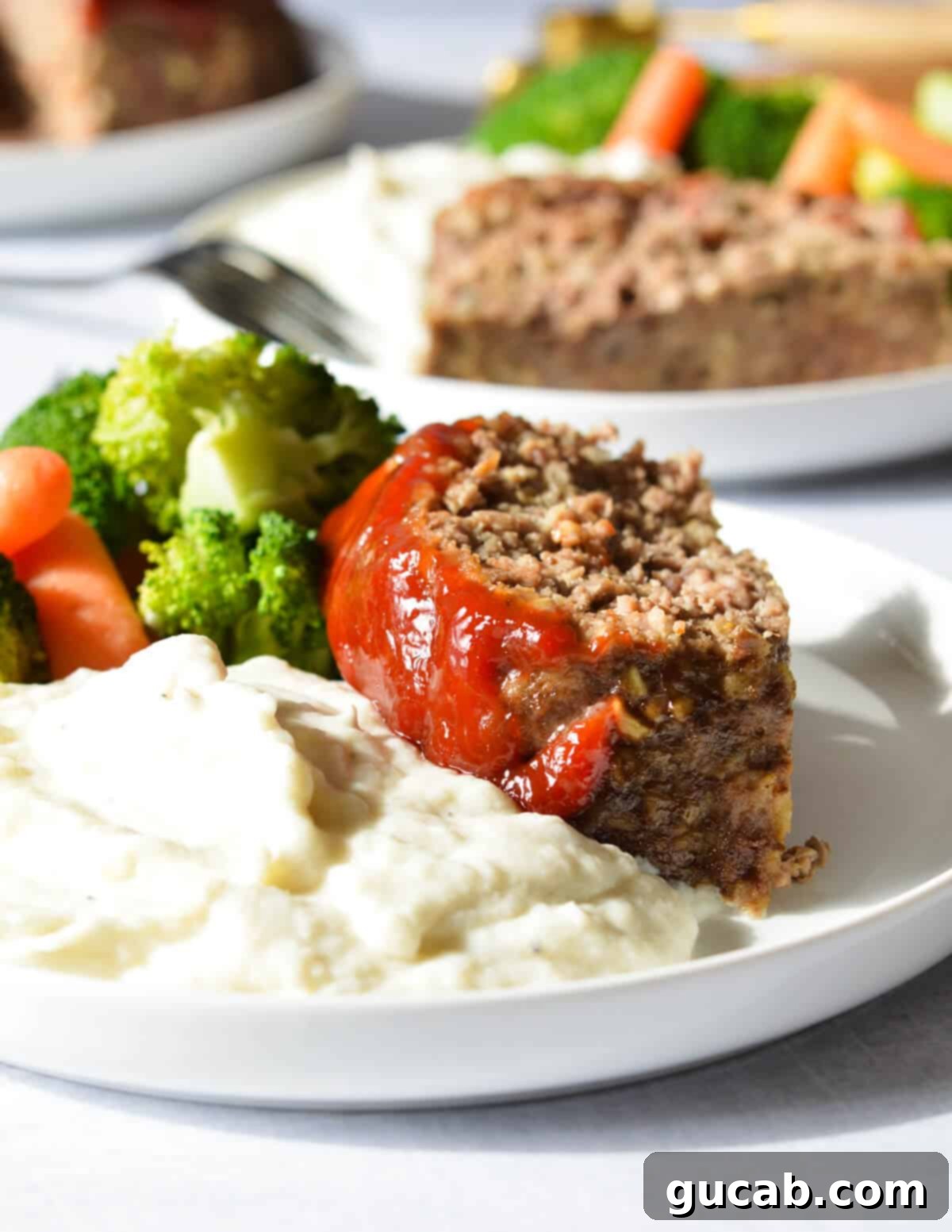 a slice of meatloaf with mashed potatoes and broccoli. 