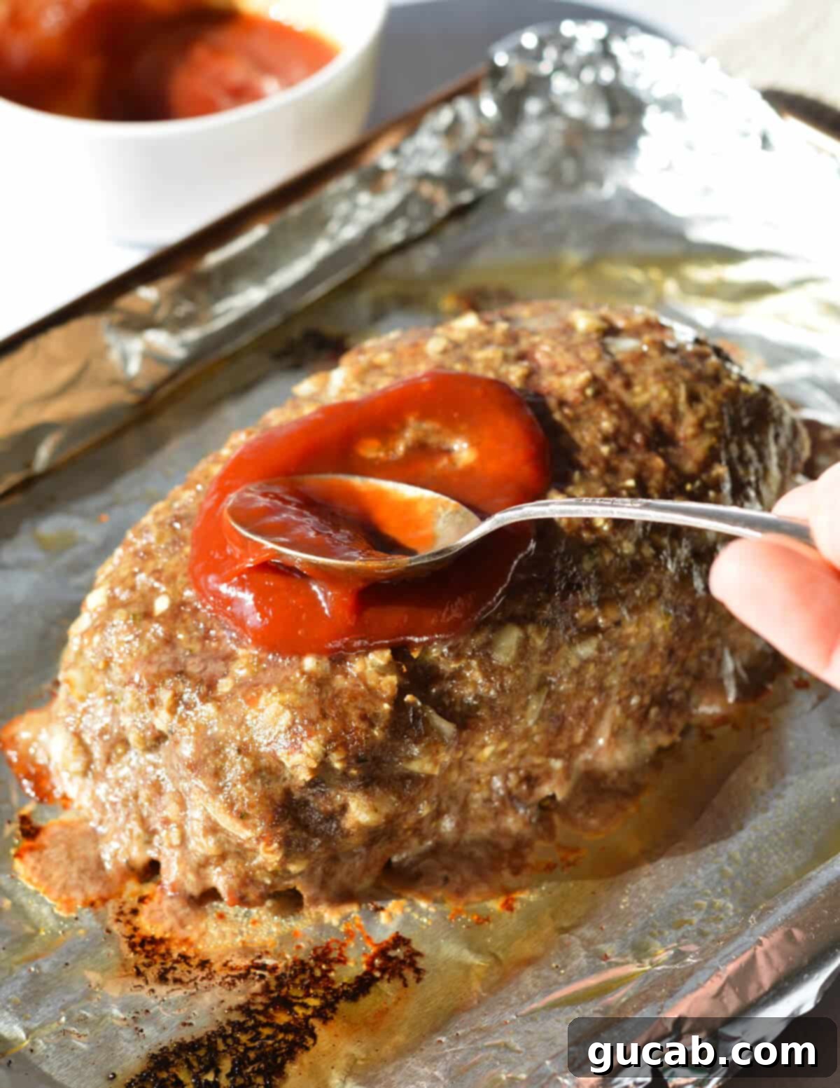 spooning a ketchup glaze onto a meatloaf.