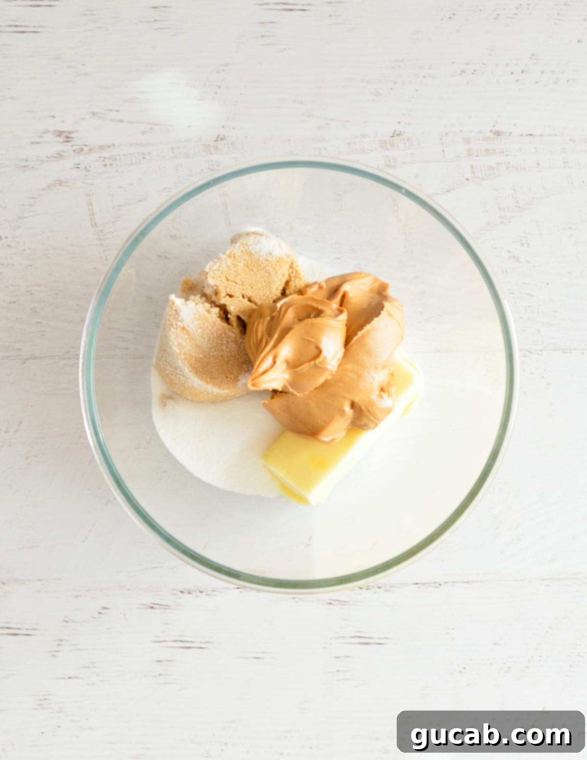 Peanut butter, softened butter, and sugars in a mixing bowl before creaming.