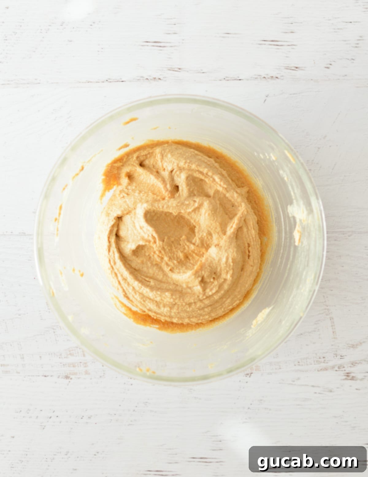 A bowl of creamed butter, sugar, and peanut butter, light and fluffy.
