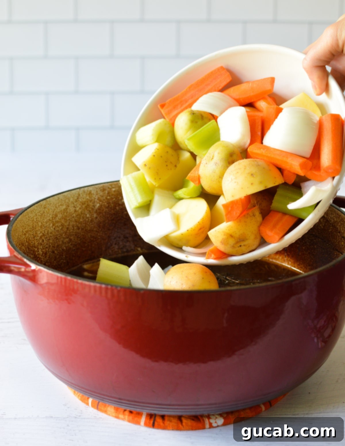 pouring a bowl of veggies into a dutch oven. 