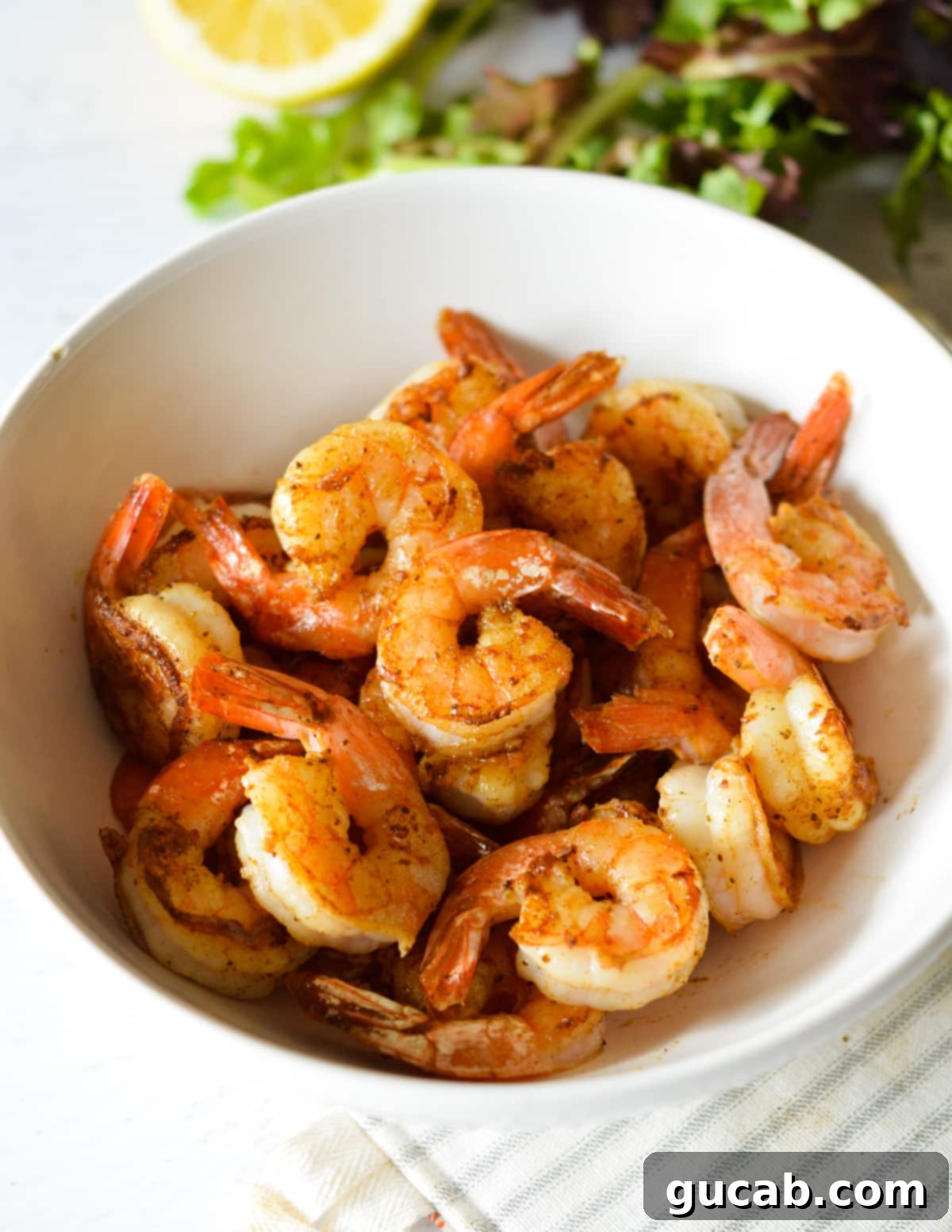 A vibrant bowl of perfectly pan seared shrimp, garnished and ready to serve.