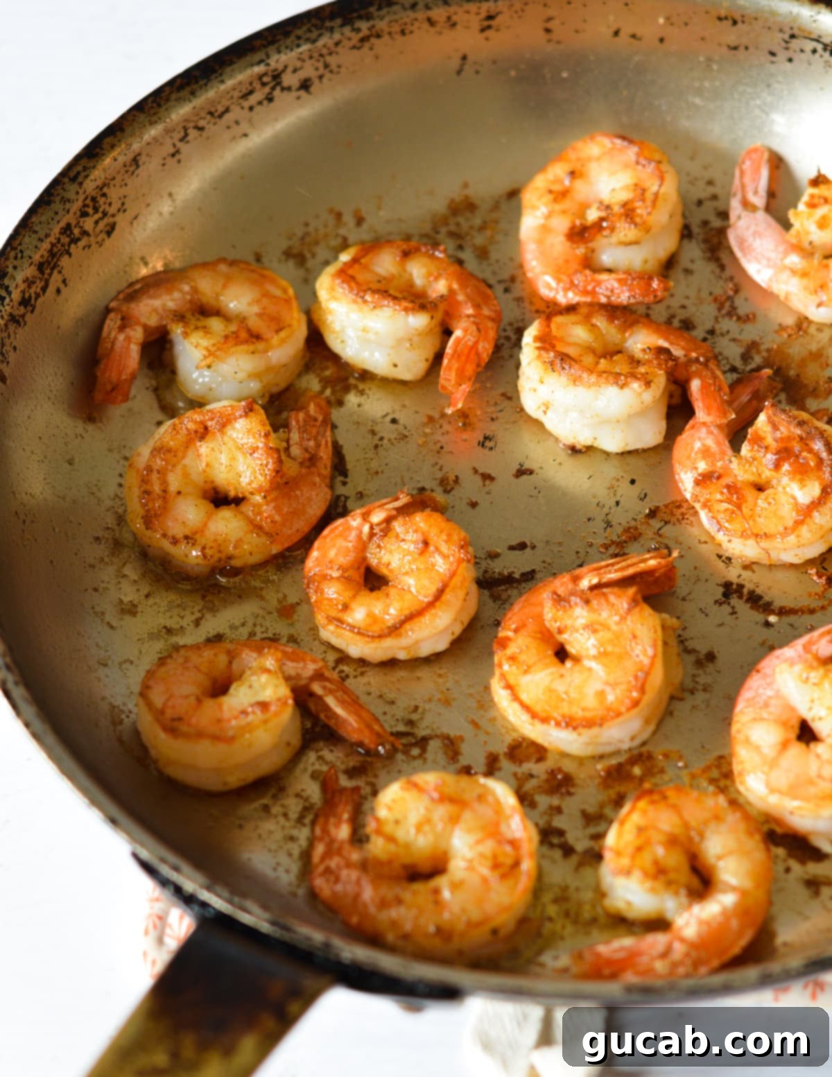 Perfectly pan seared shrimp cooking in a hot skillet, showing the golden-brown crust.