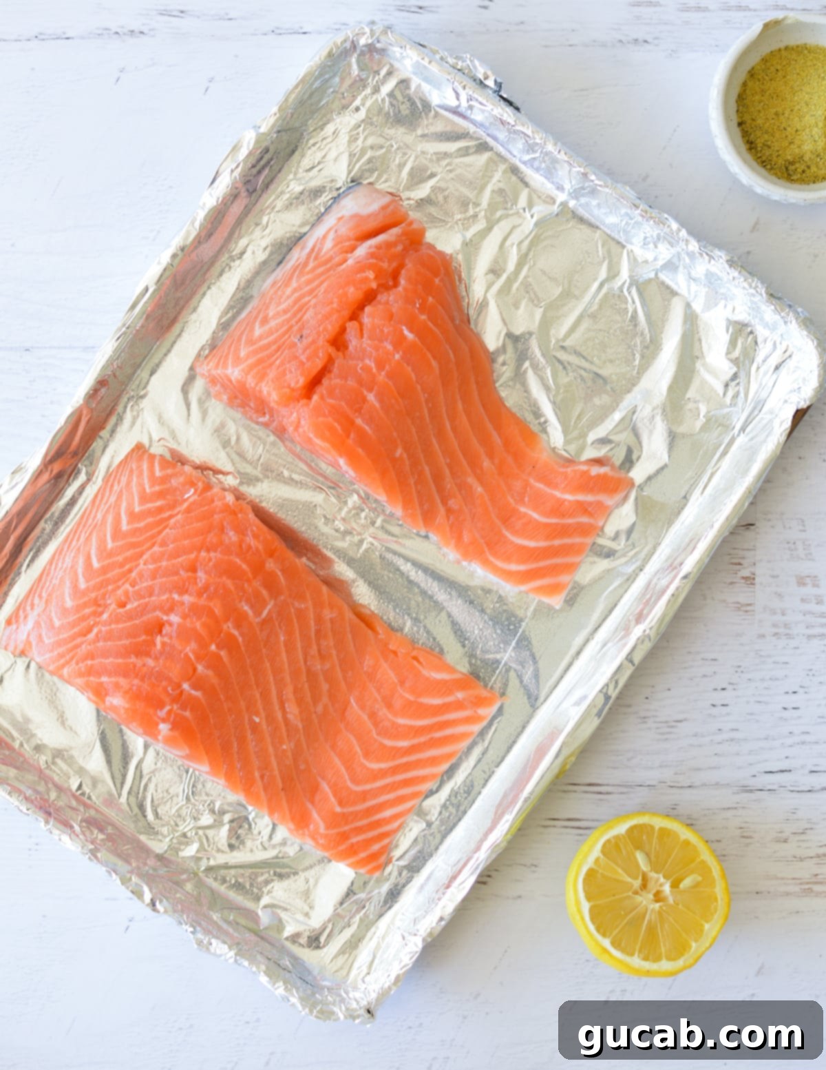salmon fillets on aluminum foil lined sheet pan.