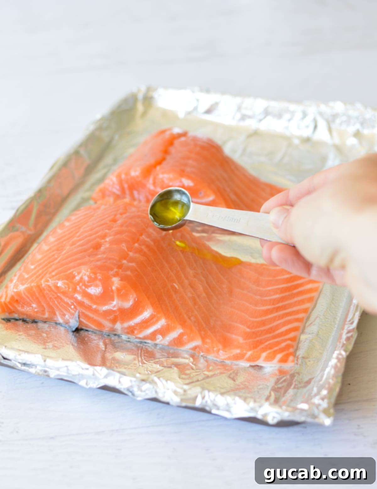 hand pouring olive oil onto a salmon fillet. 